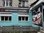 Зовнішня стіна будівлі автошколи на вулиці Миру з рекламним зображенням навчального автомобіля та переліком послуг.